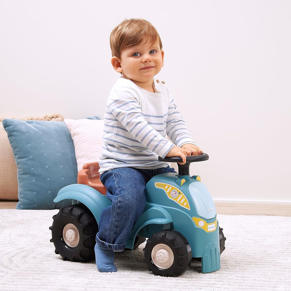 Bambino gioca con il trattore cavalcabile Ecoiffier