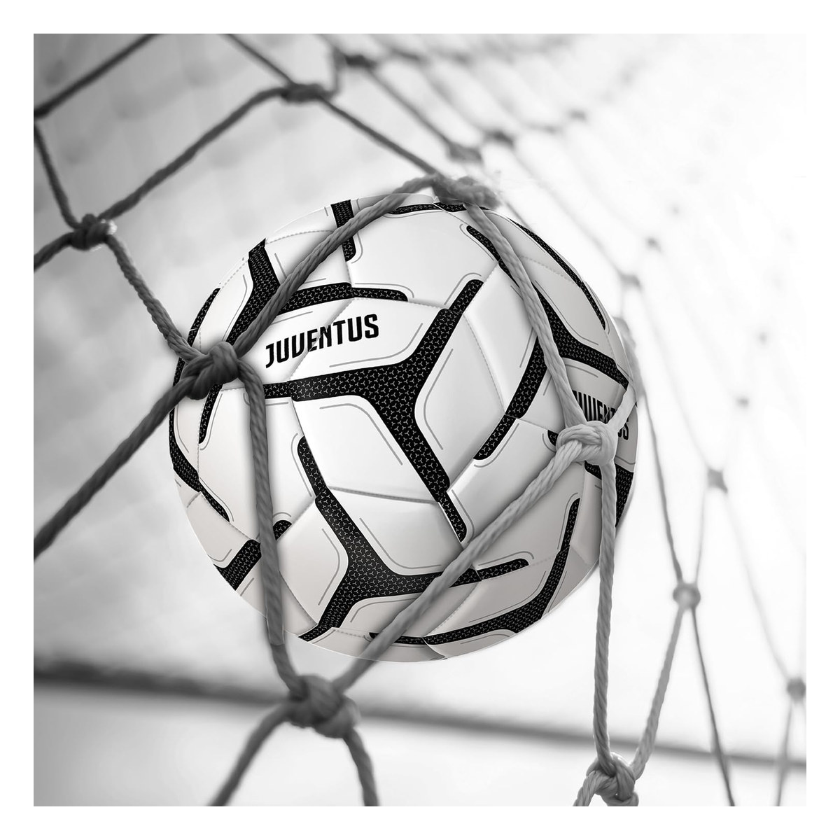 Pallone Juventus bianco e nero contro la rete di una porta da calcio, primo piano