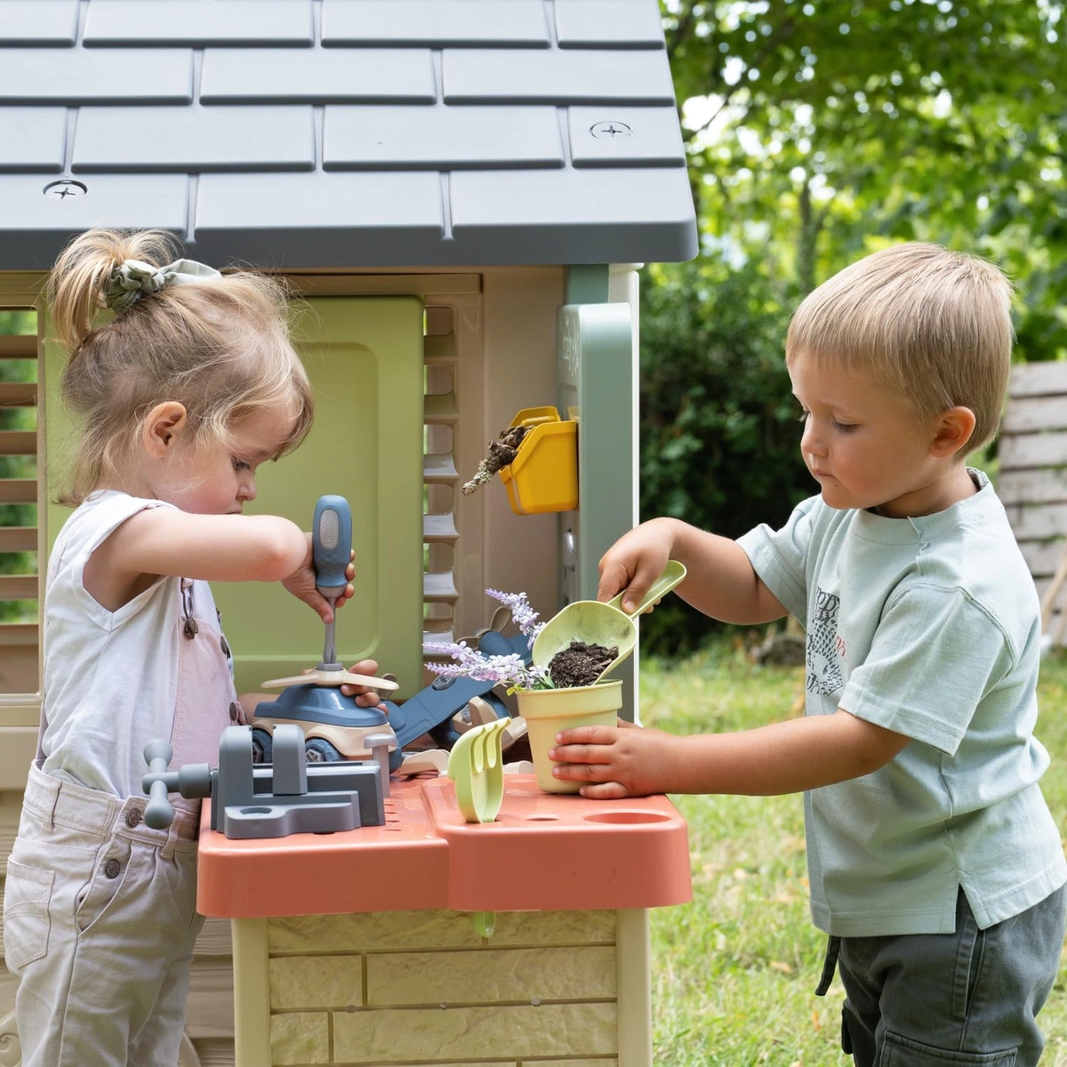 Due bambini giocano con gli attrezzi sul banco esterno Smoby Life