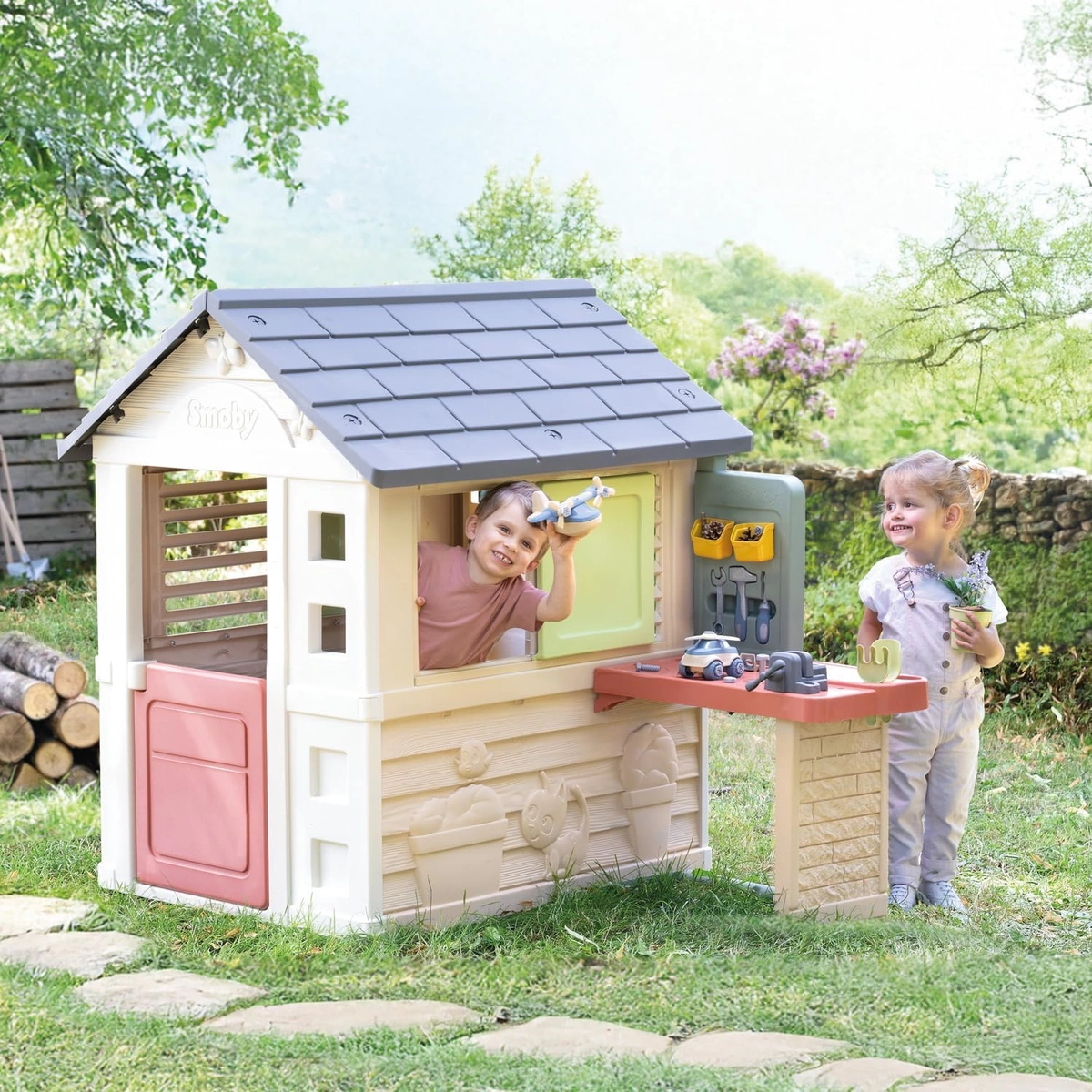 Bambine giocano in giardino con la casetta Smoby Life Natura e il banco da lavoro