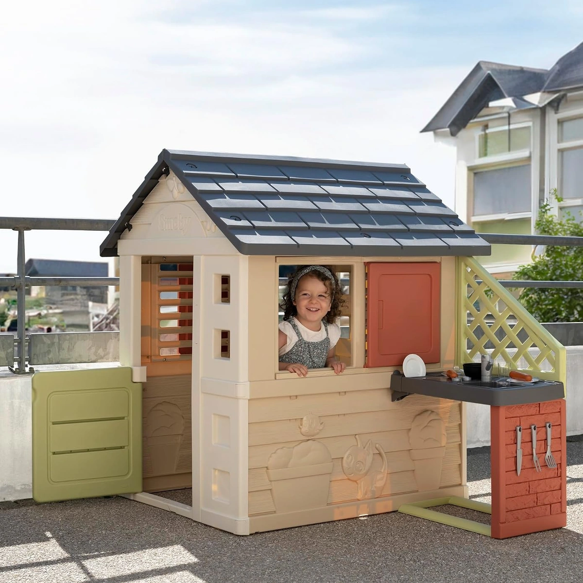 Bambina alla finestra della casetta Smoby Life Natura su terrazzo