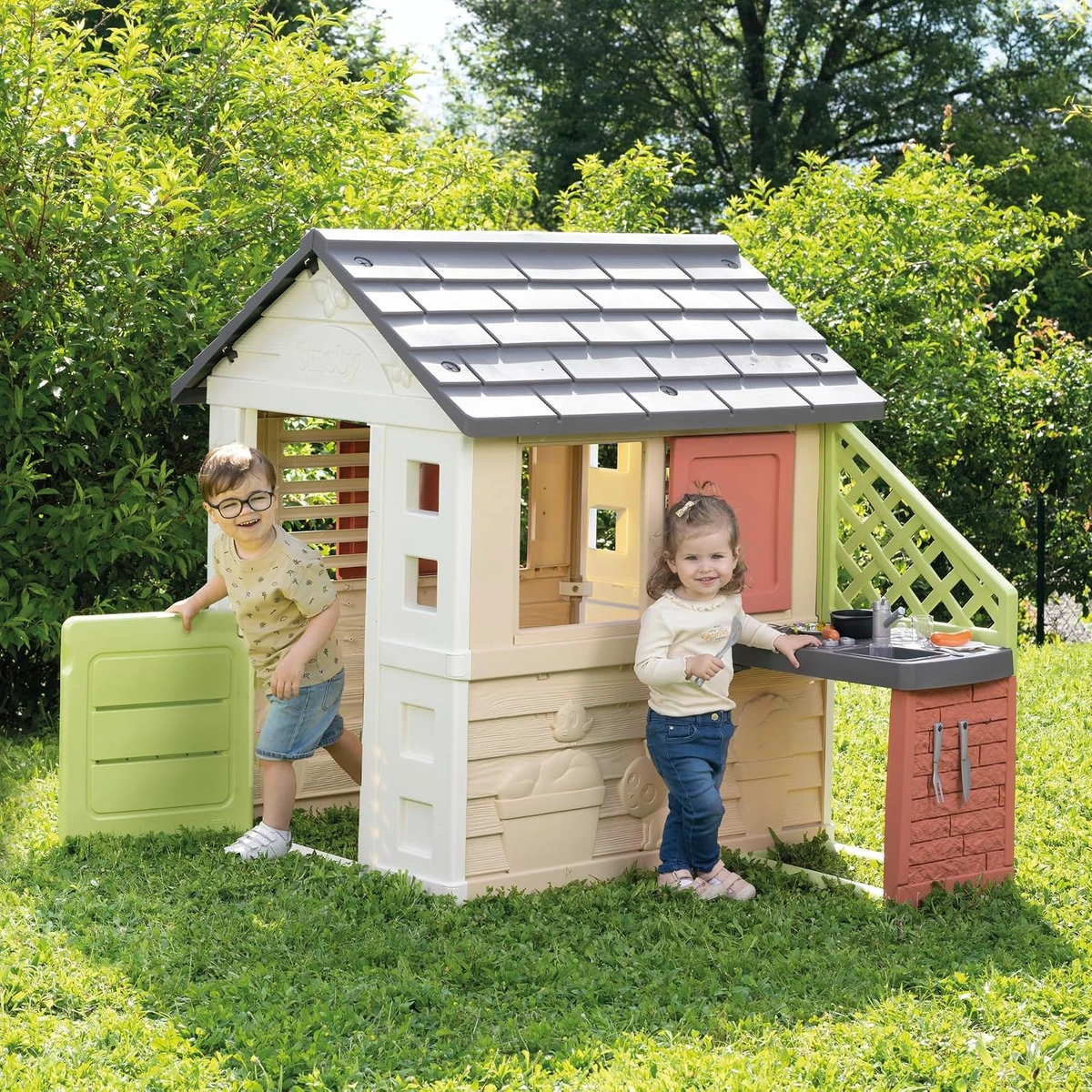 Due bambini giocano in giardino con la casetta Natura e la cucina esterna